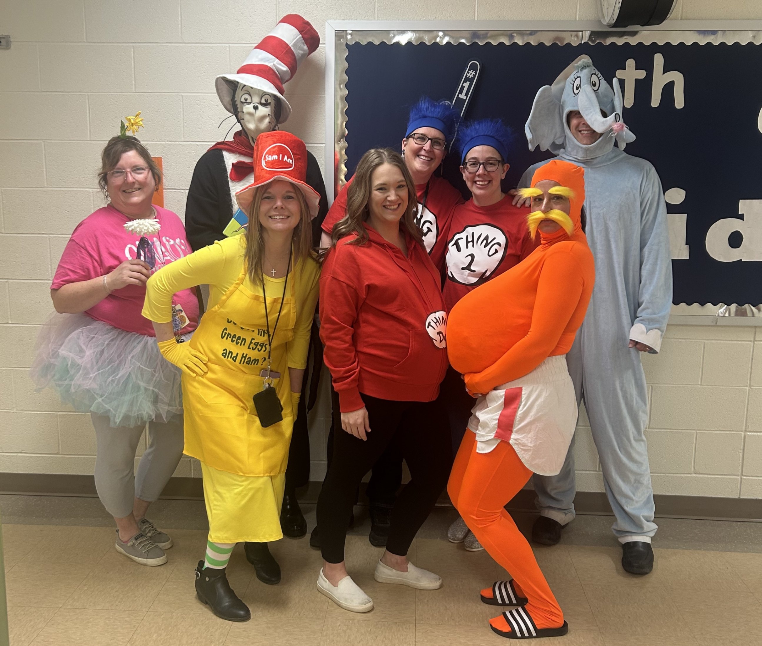 6th grade teachers dressed as Dr. Seuss characters pose for a picture with a staff member dressed as the Lorax.